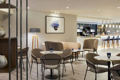 a restaurant with tables and chairs and a bar at Courtyard by Marriott London Heathrow Airport in Hillingdon
