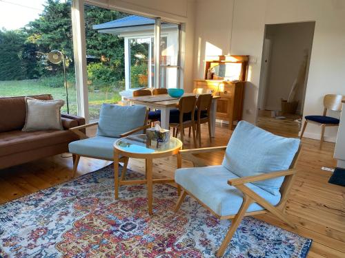 a living room with a couch and chairs and a table at WattleJack Cottage in Kingscote