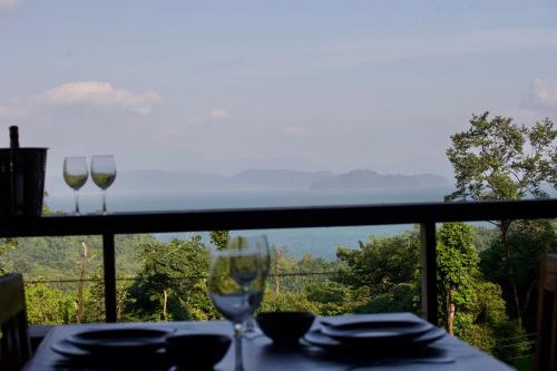 two wine glasses sitting on a table in front of a window at Baan Dee Dee in Ko Phayam