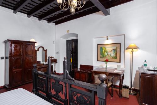 a bedroom with a bed and a desk and a table at Koder House in Cochin