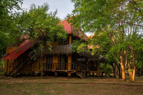 a house with a thatched roof and a porch at Cadjan Wild Yala in Kataragama