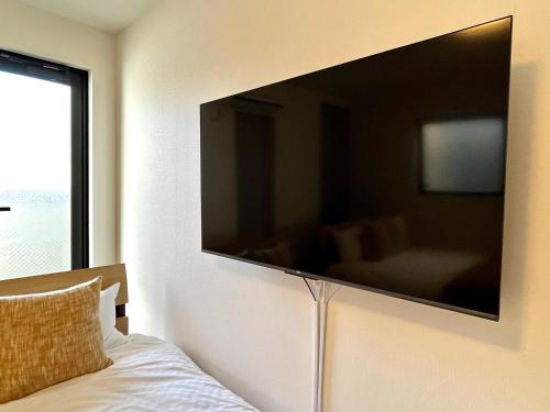 a large flat screen tv on the wall of a bedroom at Casa Nishikujo by Liaison in Osaka