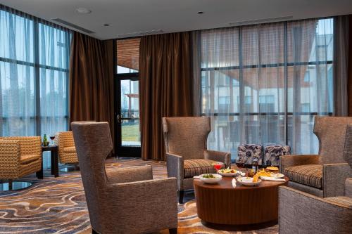 a living room with chairs and a table and windows at Courtyard by Marriott Walla Walla in Walla Walla