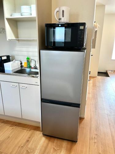 a microwave on top of a refrigerator in a kitchen at Casa Nishikujo by Liaison in Osaka