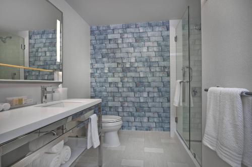 a bathroom with a toilet and a glass shower at Renaissance Edmonton Airport Hotel in Nisku
