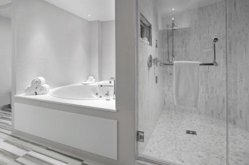 a bathroom with a shower and a tub and a sink at Renaissance Edmonton Airport Hotel in Nisku