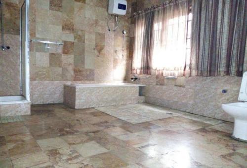 une salle de bain avec une baignoire, un lavabo et des toilettes dans l'établissement Cynergy Suites Apapa - Royal, à Lagos