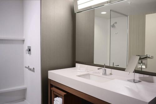 a bathroom with a sink and a mirror at Courtyard by Marriott Dallas Plano/The Colony in The Colony