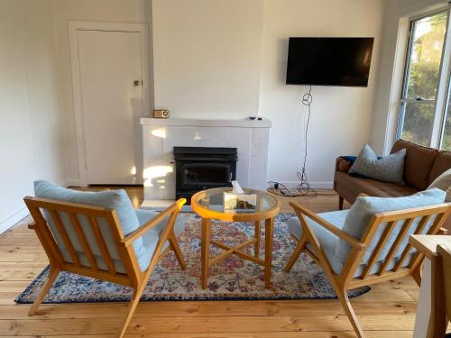 a living room with a table and chairs and a fireplace at WattleJack Cottage in Kingscote