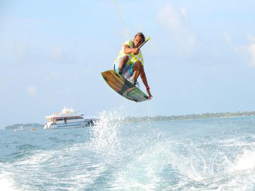 a man on a surfboard in the water with a boat at Vista Beach Retreat in Hulhumale