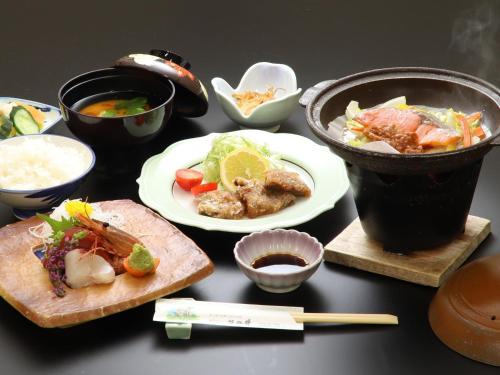 a table topped with plates of food and a drink at Simamegurinoyado Sakai in Ishinomaki