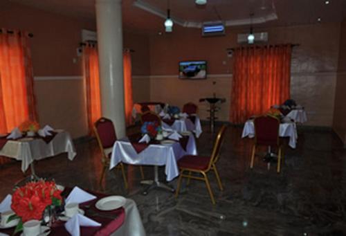 a dining room with tables and chairs and red curtains at Sheriffyt Royale Hotel Suites - Deluxe in Ikorodu