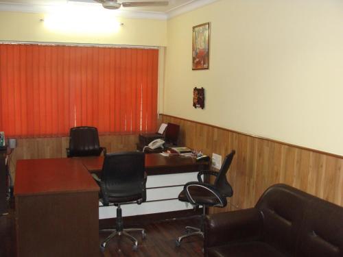 a waiting room with chairs and a desk and a red curtain at Hotel Abhinandan Grand in Dehradun