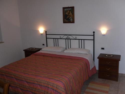 een slaapkamer met een groot bed met 2 nachtkastjes bij Agriturismo il Giardino in Saturnia
