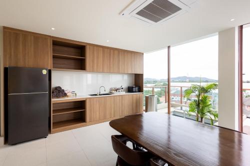 a kitchen with a wooden table and a black refrigerator at GOOD Nakhonsawan Hotel in Nakhon Sawan