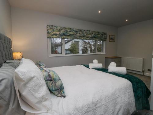 a bedroom with a large white bed with two chairs at Hazelodge in Coniston