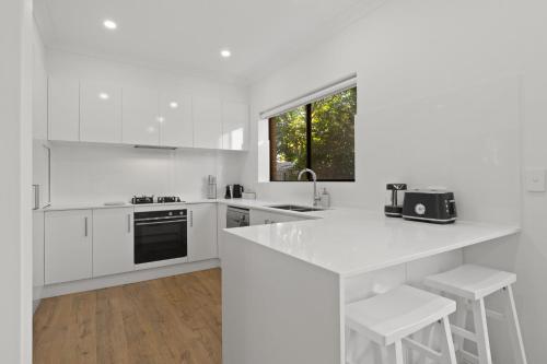 a white kitchen with a counter and a sink at Stylish 3-Bed House Close to Attractions in Glenelg
