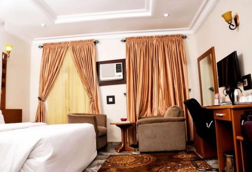 a hotel room with a bed and a chair and a desk at Hotel De Bently - Deluxe in Abuja