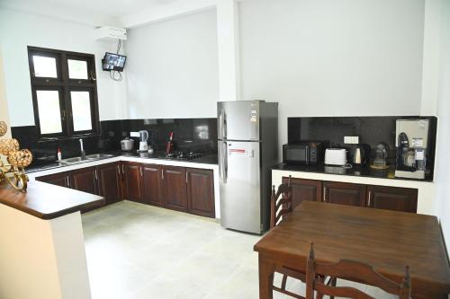 a kitchen with a stainless steel refrigerator and a table at Wind Villa Weligama Bay - Vacation House in Weligama