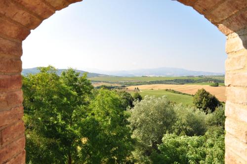 an arch in a brick wall with a view of trees at Antica Grancia Di Quercecchio in Montalcino