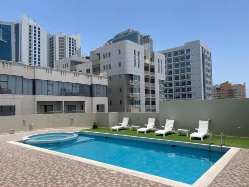 a swimming pool with lounge chairs and a building at HAVEN TOWER in Juffair