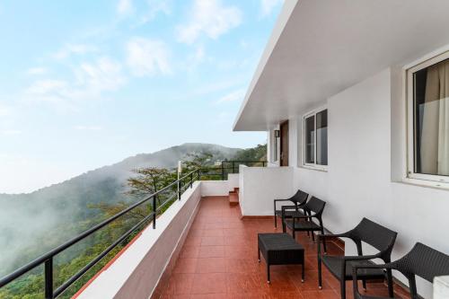 a balcony with chairs and a view of the mountains at Sterling Yercaud in Yercaud