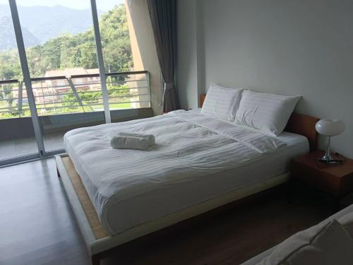 a bed in a room with a large window at La Foresta Khaoyai in Pak Chong