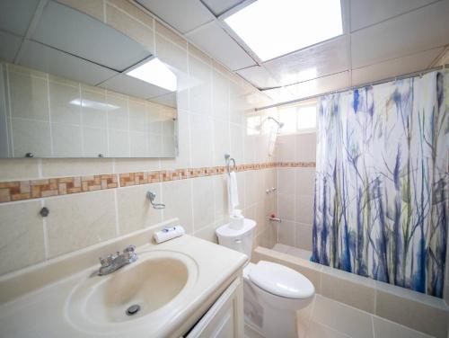 a bathroom with a sink and a toilet and a shower curtain at Garden Condos 10, 2br Apt In Sosua Strip in Sosúa