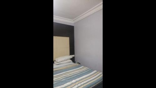 a small bedroom with a bed with a striped blanket at Prince Of Anthony 1960 Hotel-apartment in Lagos