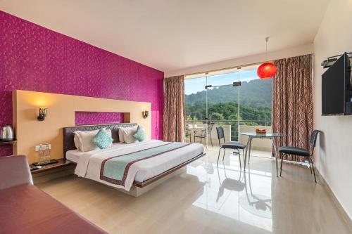 a bedroom with pink walls and a bed and a table at Sterling Yelagiri in Yelagiri