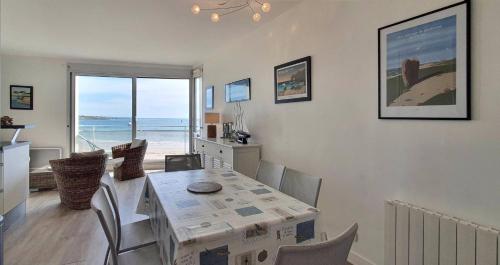 une salle à manger avec une table et une vue sur l'océan dans l'établissement Escale sur la Grande Plage, à Quiberon