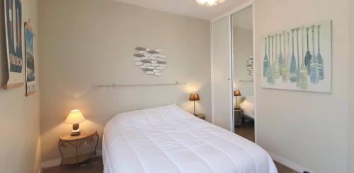 une chambre blanche avec un lit et un miroir dans l'établissement Escale sur la Grande Plage, à Quiberon