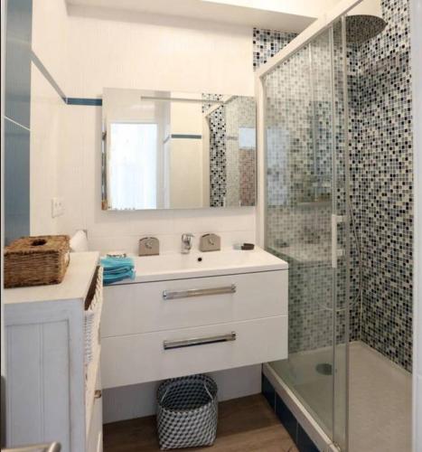 une salle de bain blanche avec un lavabo et une douche dans l'établissement Escale sur la Grande Plage, à Quiberon