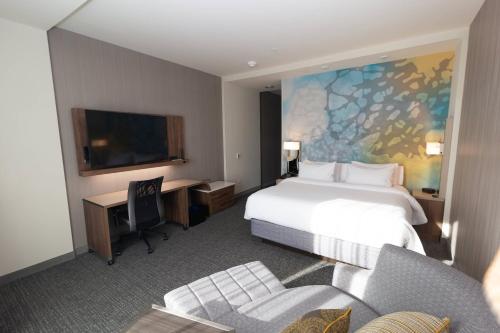 a hotel room with a bed and a desk and a tv at Courtyard by Marriott Cartersville in Cartersville