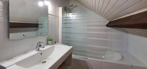 a white bathroom with a sink and a shower at La villa les pieds dans leau in Saint-Pierre-Quiberon