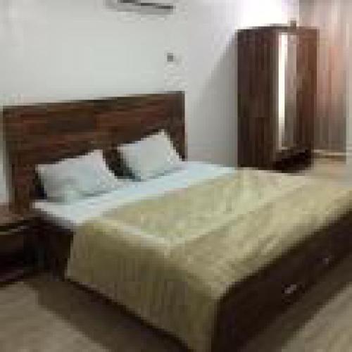 a bedroom with a large bed with a wooden headboard at Royal Signature Suites and Apartments in Ibadan