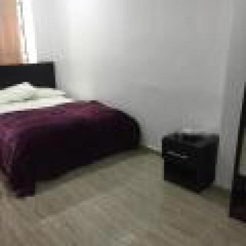 a bedroom with a bed and a night stand at Royal Signature Suites and Apartments in Ibadan