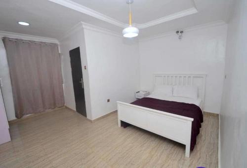 a bedroom with a bed in a white room at Royal Signature Suites and Apartments in Ibadan