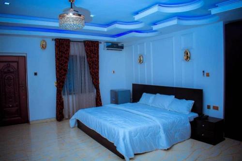 a blue bedroom with a bed and a blue ceiling at Mexiloyd Suites Queen Apartment in Port Harcourt