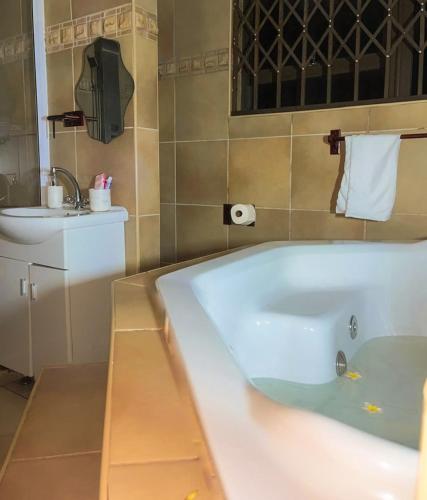 a bathroom with a bath tub and a sink at Emmanuel-Guest-House in Richards Bay