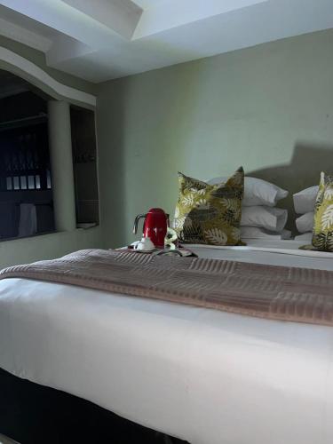 a large white bed with a tea kettle on it at Emmanuel-Guest-House in Richards Bay