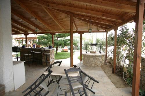 a patio with a table and chairs under a wooden pergola at Argo Hotel in Agioi Apostoli