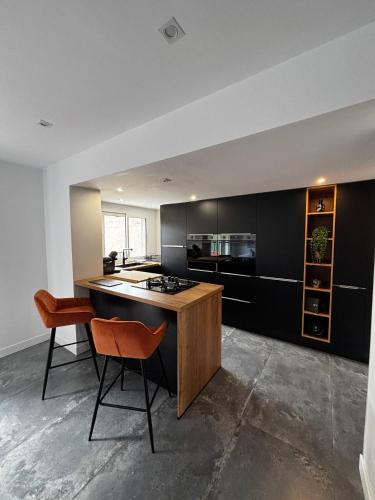 - une cuisine avec des armoires noires et un îlot en bois dans l'établissement Maison Canet Confort Moderne Prs De La Plage, à Canet