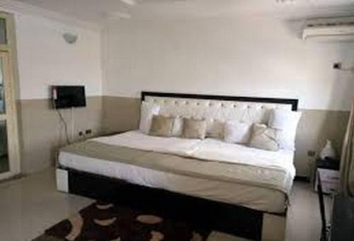 a bedroom with a large white bed with white pillows at Goldenland Hotels - Executive in Asaba