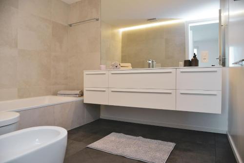 a bathroom with a sink and a tub and a toilet at Stunning Lake View Apartment by Feel Ticino Feel Home in Melide