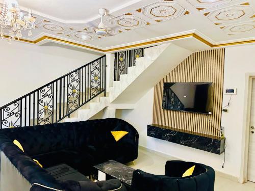 a living room with a black couch and a tv at Villa Amina splendid and elegant in Ouagadougou