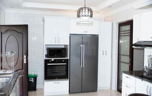 a kitchen with a refrigerator and a microwave at Lusaka Luxe - Your Private Oasis Awaits in the Heart of Zambia in Lusaka