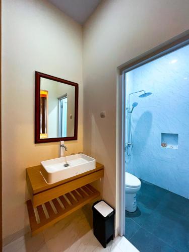 a bathroom with a sink and a mirror and a toilet at The Cabin Hotel Lovina Bali in Pulau Temukus