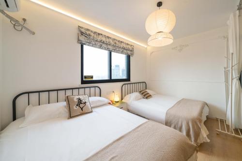 two beds in a white room with a window at Shanghai Yi Du B&B - Family Suite 500m to Nanjing West Rd Near People's Square -Credit Cards Accepted in Shanghai