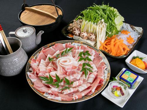 a table with two plates of meat and vegetables at Aqua Garden Hotel Fukumaru in Kagoshima